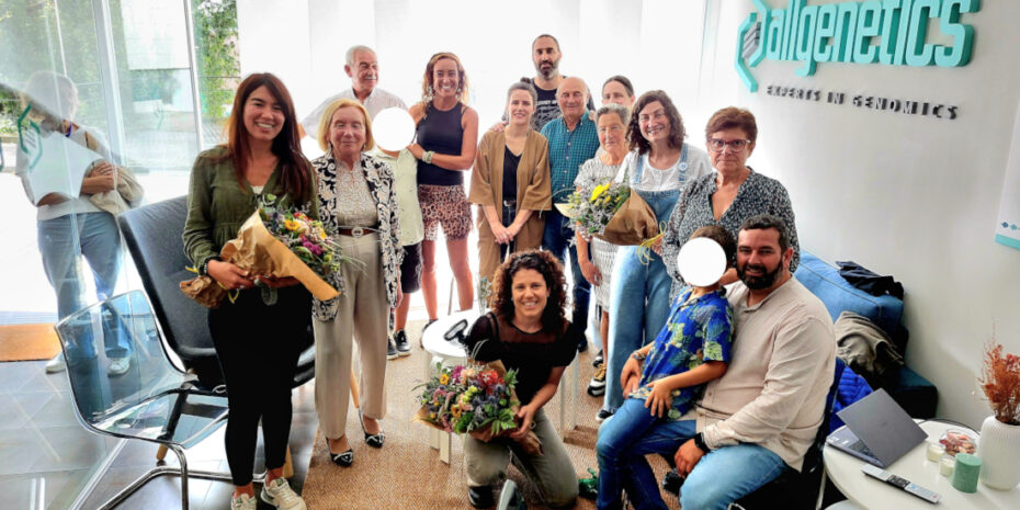 The image shows Dr Verónica Rojo, Dr Belén Carro, and Dr Neus Marí-Mena with their families at the AllGenetics' headquarters.